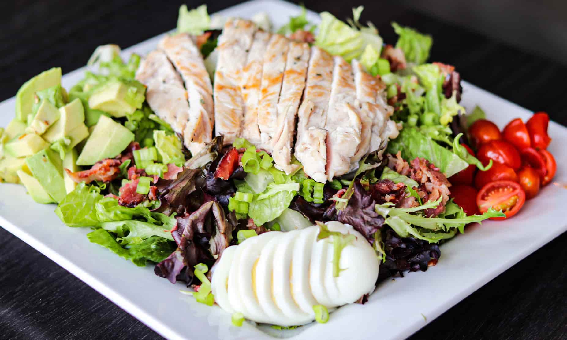 Grilled chicken sliced on top of salad