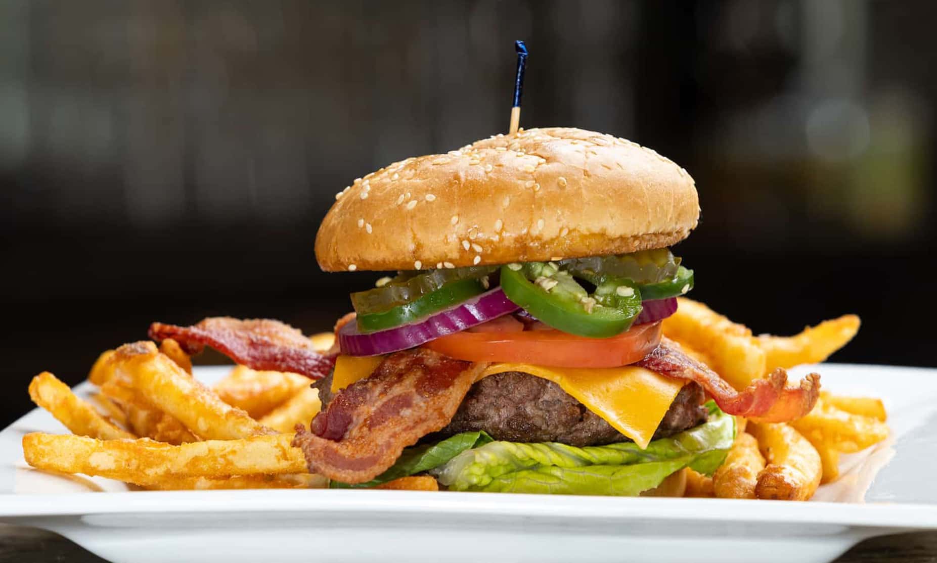 Hurrdat Sports Bar and Grill Burger topped with bacon and jalapeno with side of Fries